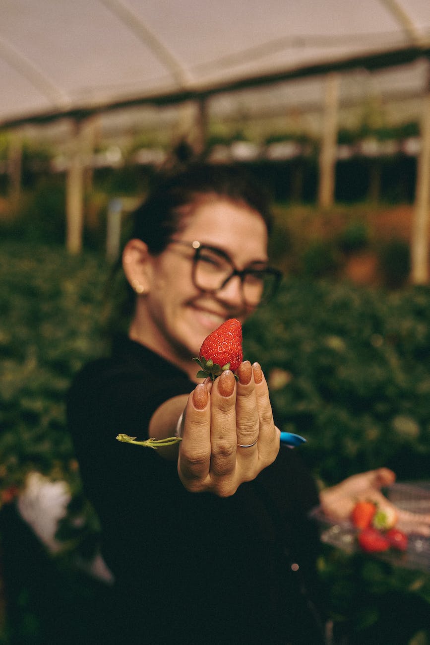woman holding a freshly picked strawberry