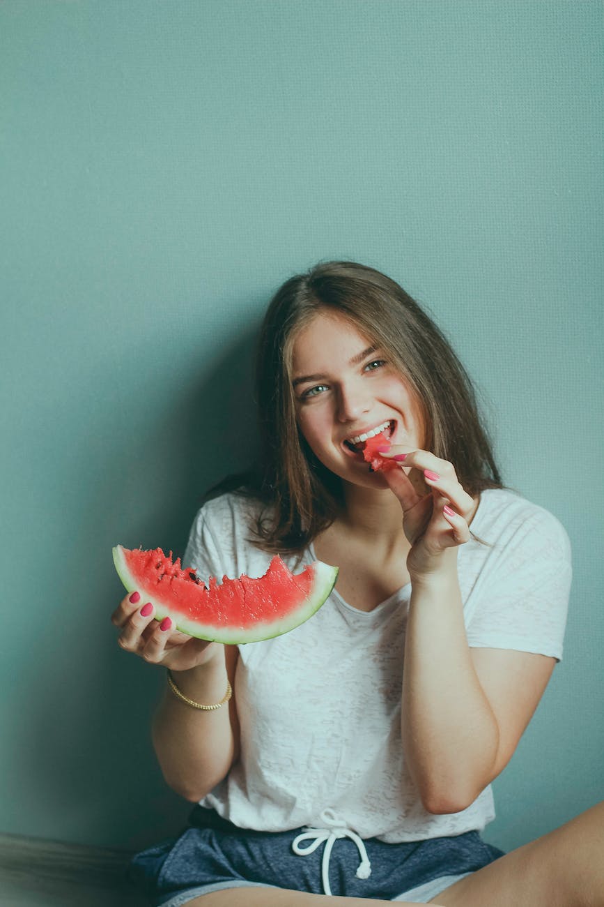 woman wearing white shirt eating watermelon