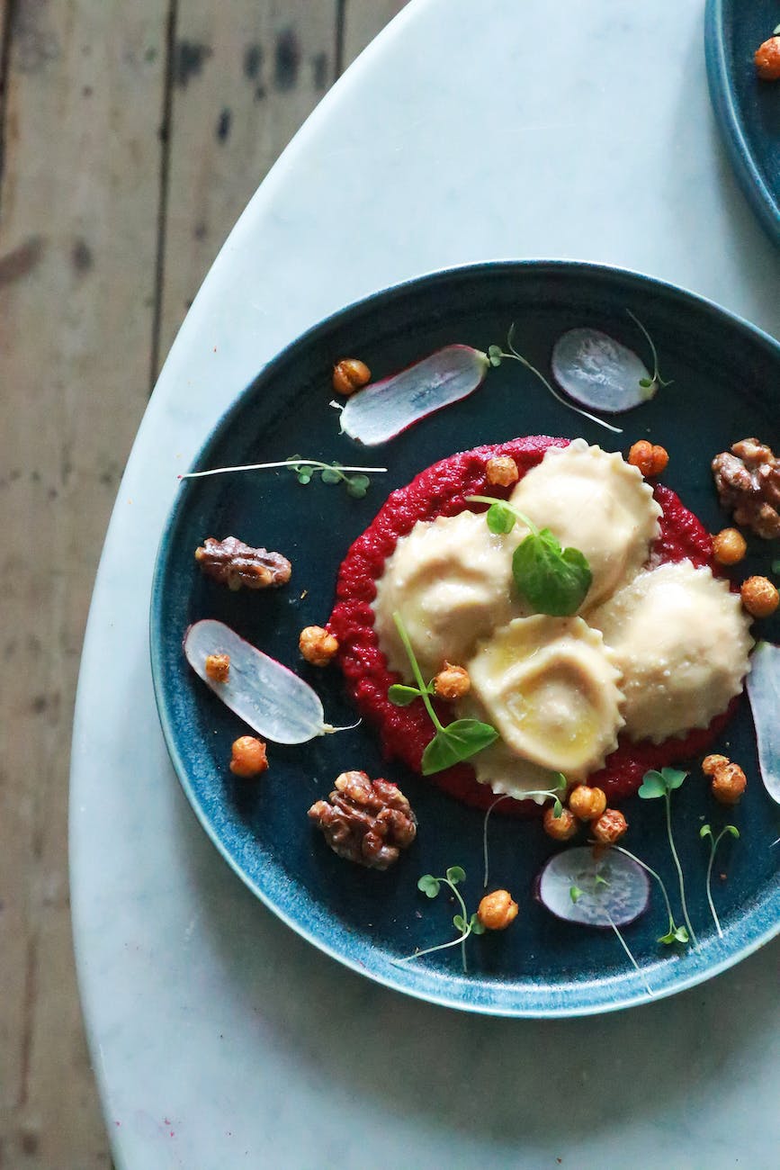 plate of tasty ravioli with beet sauce served on plate with nuts and herbs