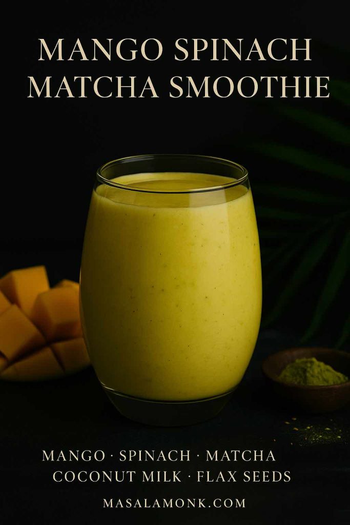 A golden mango spinach matcha smoothie in a tumbler glass, with mango cubes and matcha powder styled elegantly.
