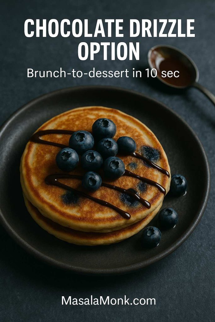 Portrait photo of blueberry pancakes on a dark plate with a chocolate drizzle and fresh blueberries, featuring text overlay “Chocolate Drizzle Option” and “Brunch-to-dessert in 10 sec,” with MasalaMonk.com in the footer.