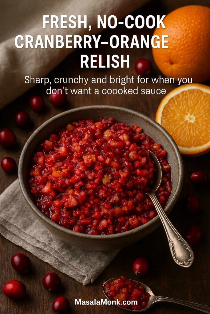 Bowl of fresh no-cook cranberry orange relish with a spoon, surrounded by whole cranberries and orange halves on a wooden table.