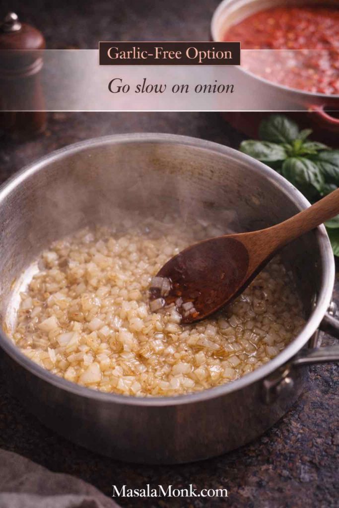 Onions slowly cooking in a saucepan with basil nearby and no garlic present, showing the base technique for a garlic free marinara sauce.