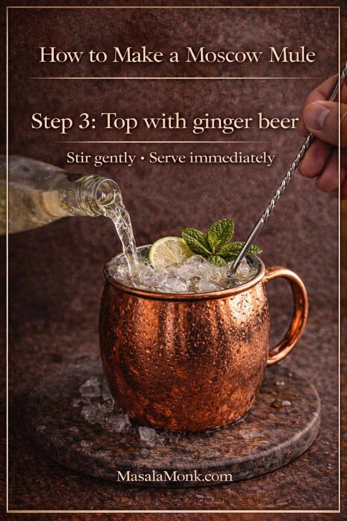 How to make a Moscow Mule step 3: pouring chilled ginger beer into a copper mug with ice, lime and mint, with a gentle stir to keep the Moscow mule recipe fizzy.