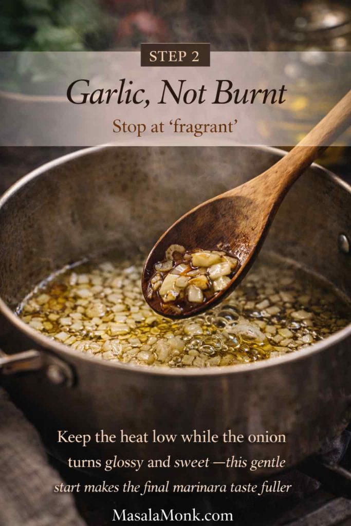 Garlic gently sizzling in olive oil with softened onion in a saucepan, showing step 2 of a homemade marinara sauce recipe before adding tomatoes.