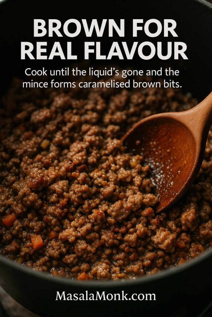 Close-up of minced beef and pork browning with soffritto in a cast-iron pot, showing the liquid cooked off and caramelised brown bits forming for authentic bolognese flavour.