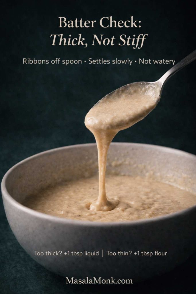 Close-up portrait guide showing waffle batter without milk dripping in a smooth ribbon from a spoon into a bowl, with text overlay “Batter Check: Thick, Not Stiff” and tips for adjusting batter that’s too thick or too thin, plus MasalaMonk.com in the footer.