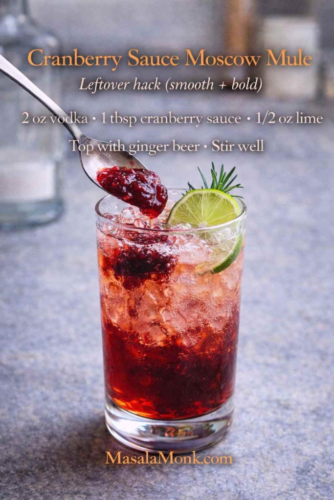 Cranberry sauce Moscow mule in a tall glass with a spoonful of cranberry sauce, lime wheel, and rosemary, with an on-image recipe for a leftover cranberry sauce mule.