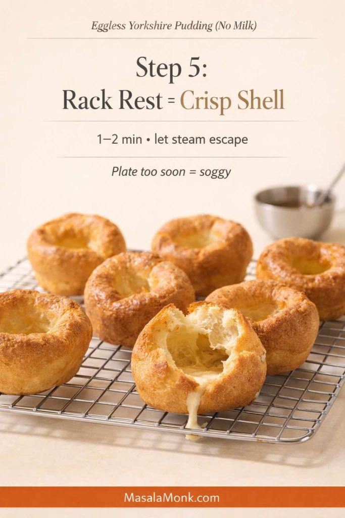 Eggless Yorkshire puddings cooling on a wire rack, with one torn open to show a hollow center; text overlay explains Step 5 for Yorkshire pudding without milk: rest 1–2 minutes so steam escapes and the shell stays crisp, with MasalaMonk.com in the footer.