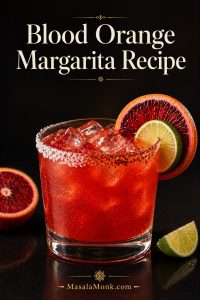 Blood orange margarita in a rocks glass with ice, a half salt and Tajín rim, blood orange and lime garnish, and a dark editorial background.