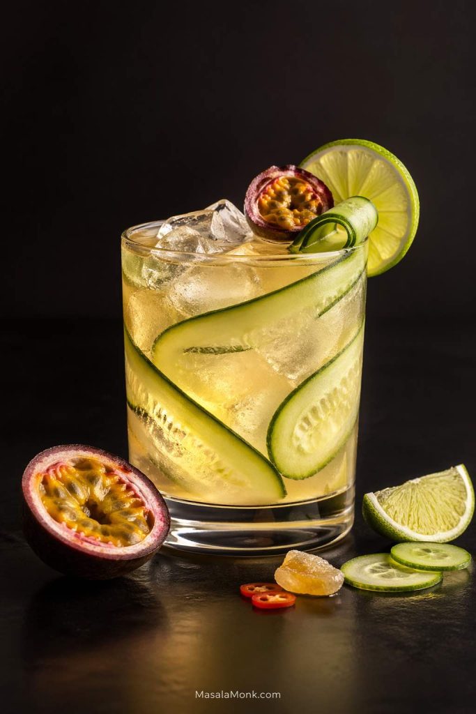 Cocktail-bar mezcal mule riff with cucumber, passion fruit, lime, ice, and a pale golden drink in a clear glass.