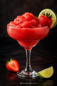 Frozen strawberry daiquiri recipe in a coupe glass with strawberry and lime garnish on a dark editorial background