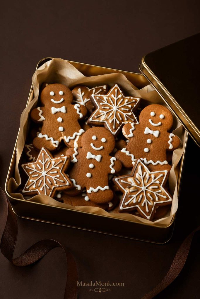 Decorated gingerbread cookies packed in a parchment-lined tin for gifting after the icing has fully dried and set.