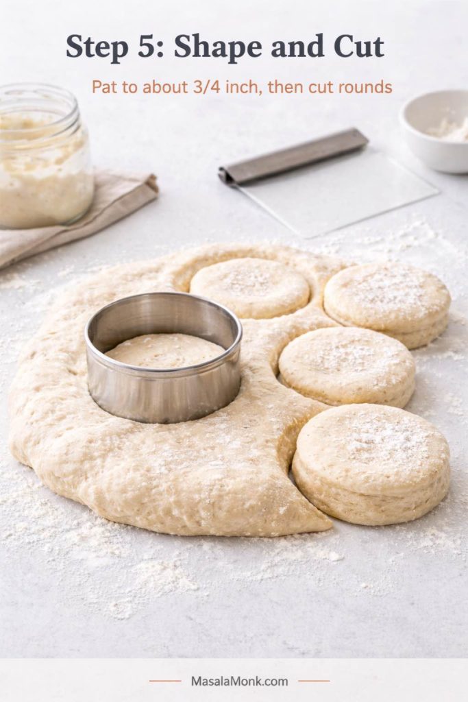 Step 5 process image for sourdough English muffins showing thick dough patted to about 3/4 inch on a lightly floured surface, with a cutter cutting rounds and several soft cut muffins visible beside the dough.