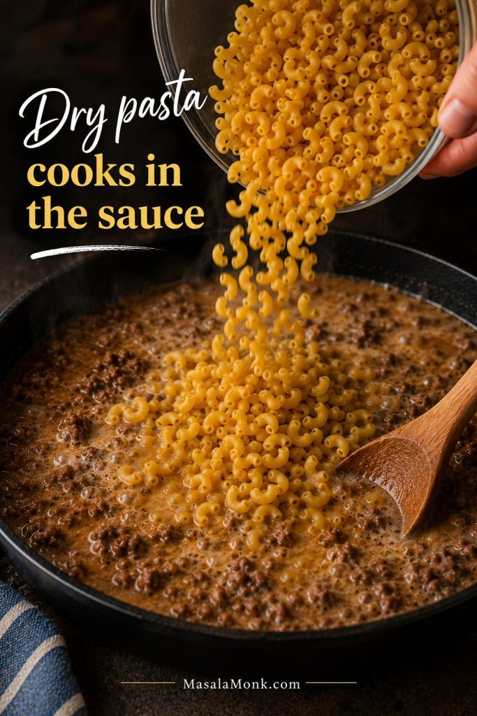 Dry elbow macaroni being added to a skillet with ground beef, broth, and milk for one-pot homemade Hamburger Helper.