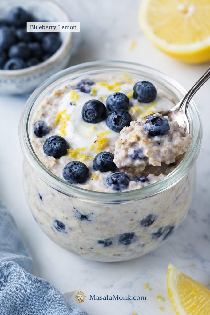 Blueberry lemon overnight oats with fresh blueberries, lemon zest, creamy oats, and a spoon lifting a bite.