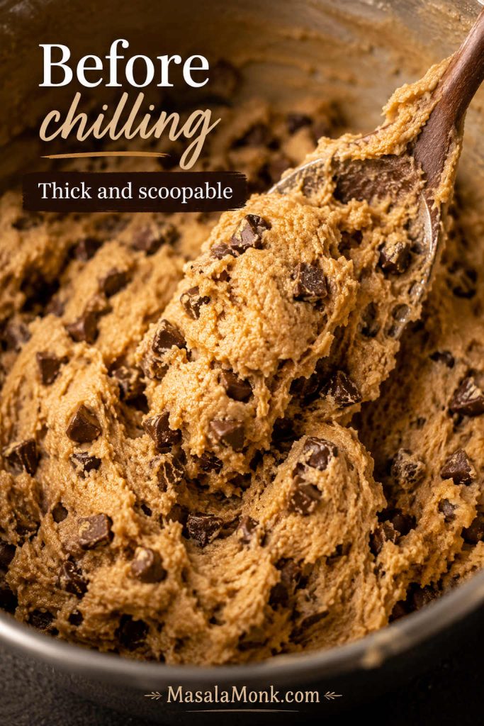 Thick brown butter chocolate chip cookie dough with chocolate pieces before chilling, shown with a spatula in the bowl.