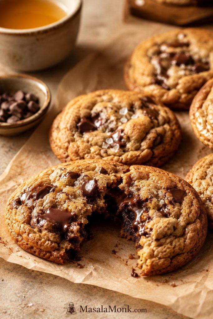 Brown butter chocolate chip cookies with soft rippled tops, glossy melted chocolate, and a cracked chewy center.
