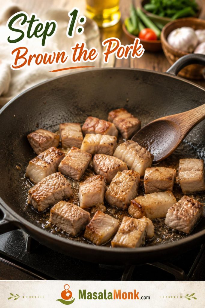 Pork pieces browning in a wide pan at the beginning of making Pinakbet Tagalog.