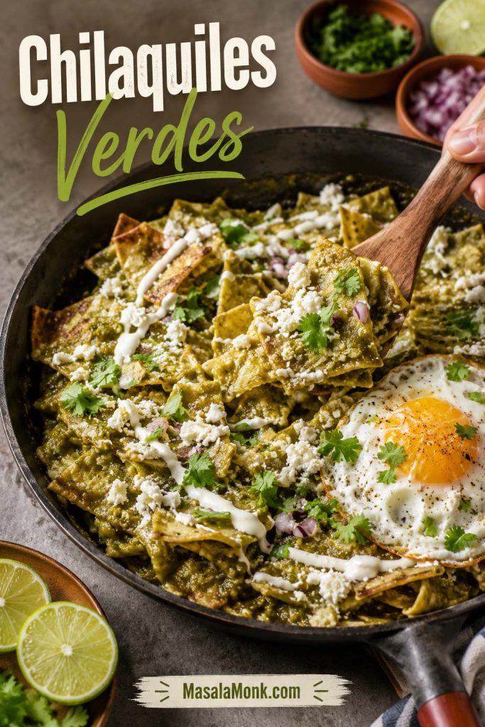 Chilaquiles verdes in a skillet with tortilla chips, salsa verde, egg, crema, cilantro, onion, and cheese