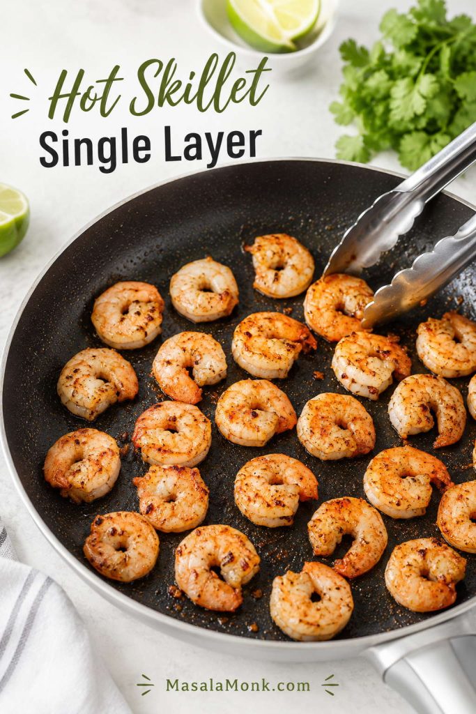 Seasoned shrimp cooking in a single layer in a hot skillet with tongs