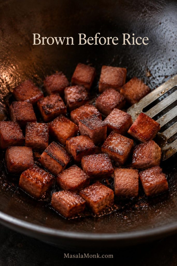 Cubes of Spam browning in a skillet until the edges look crisp and caramelized.