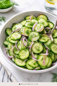Bowl of cucumber salad with thin cucumber slices, red onion, fresh dill, black pepper, and a light vinegar dressing.