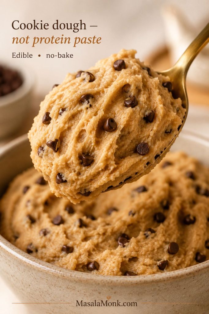 Spoon lifting edible protein cookie dough with mini chocolate chips and soft ridges showing the scoopable texture