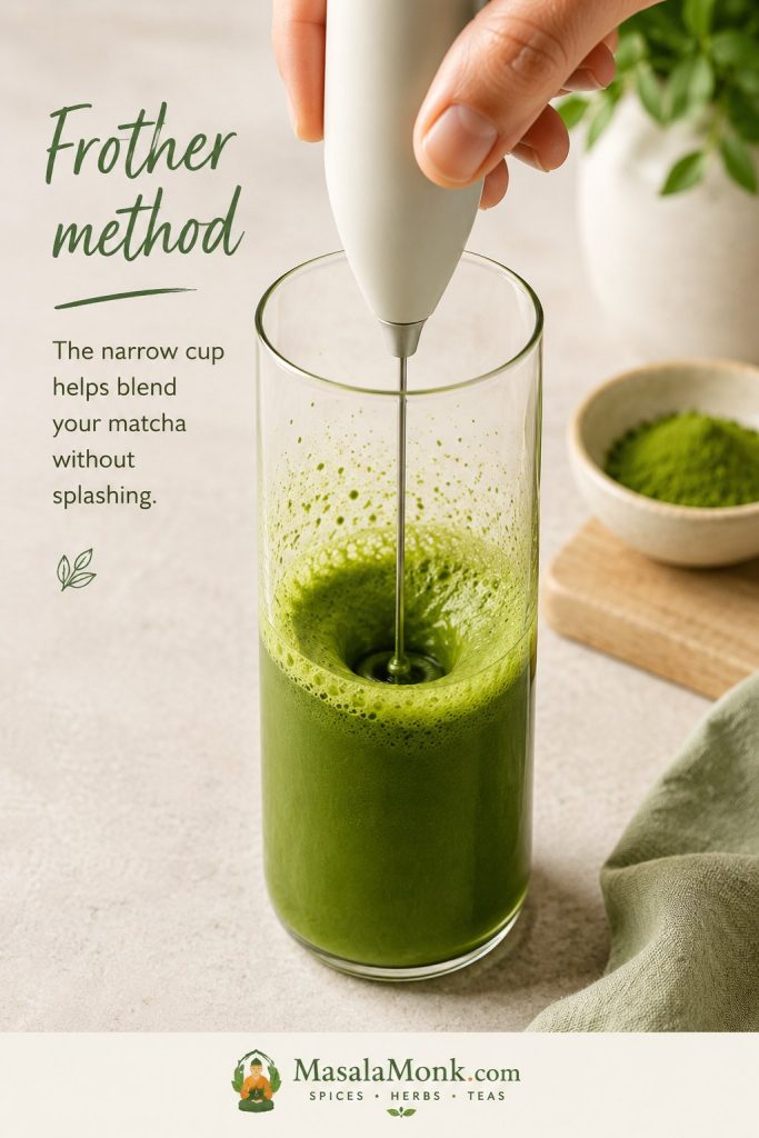 Handheld frother blending matcha in a tall narrow cup
