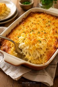 Golden hashbrown casserole in a baking dish with a scoop lifted to show the creamy shredded potato center.