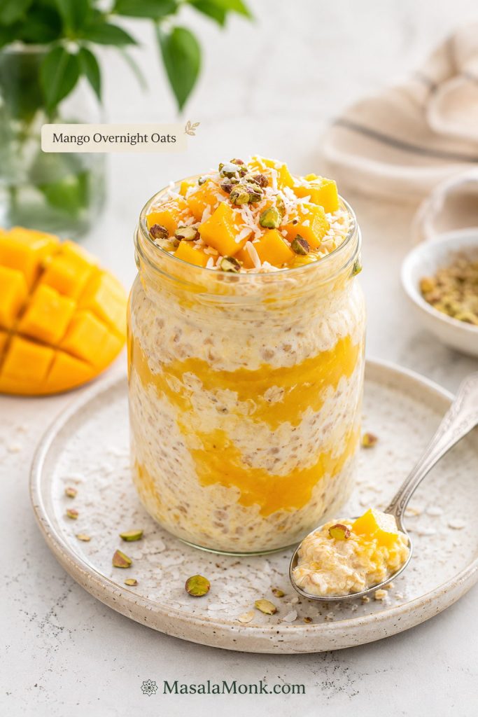 Mango overnight oats with creamy oats, mango puree, fresh mango cubes, coconut, and pistachios.