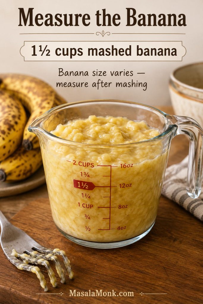 Mashed banana measured to 1½ cups in a glass measuring cup with ripe bananas and a fork nearby.