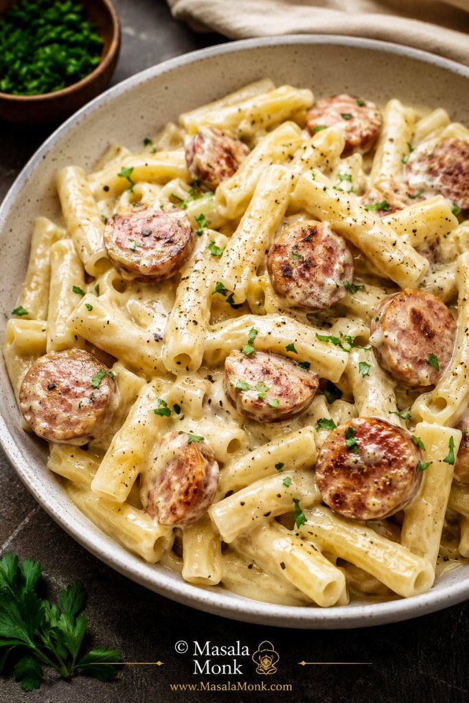 No-tomato kielbasa pasta with pale cream sauce, browned sausage slices, short pasta, black pepper, and parsley.