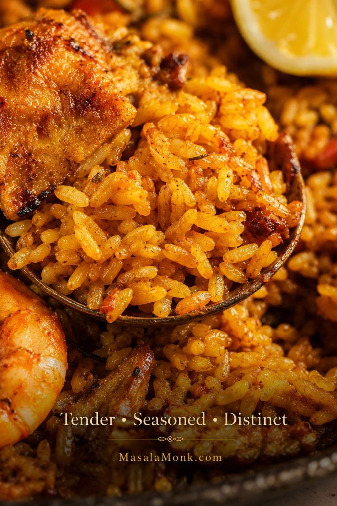 Close-up of paella rice with tender separate saffron grains, shrimp, chicken, and a moist but not soupy texture.