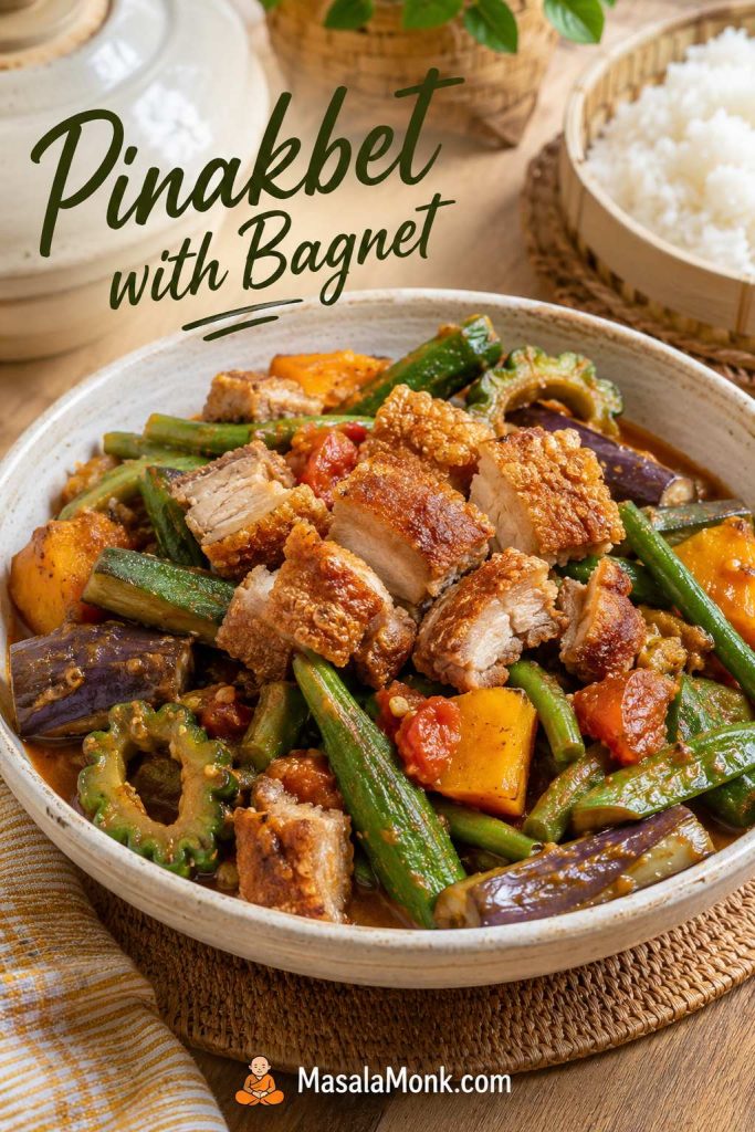 Pinakbet with crispy bagnet pieces on top, mixed vegetables, glossy sauce, and rice nearby.