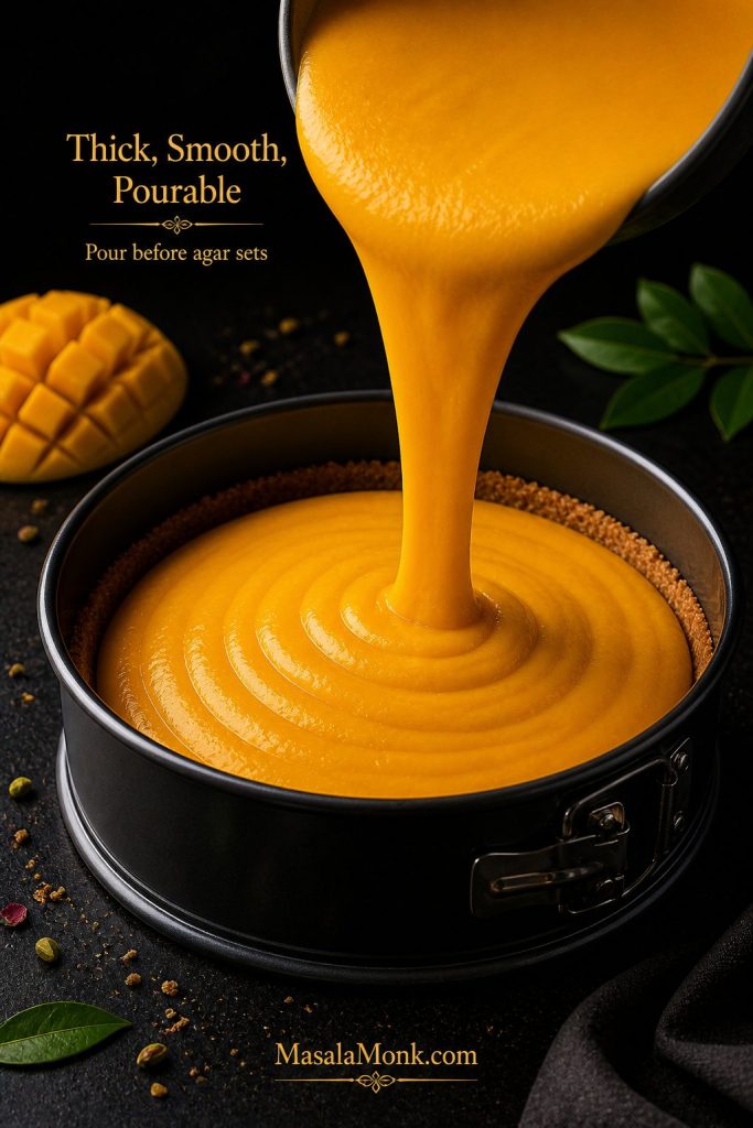 Thick mango cheesecake filling being poured into a springform pan with a prepared biscuit crust.