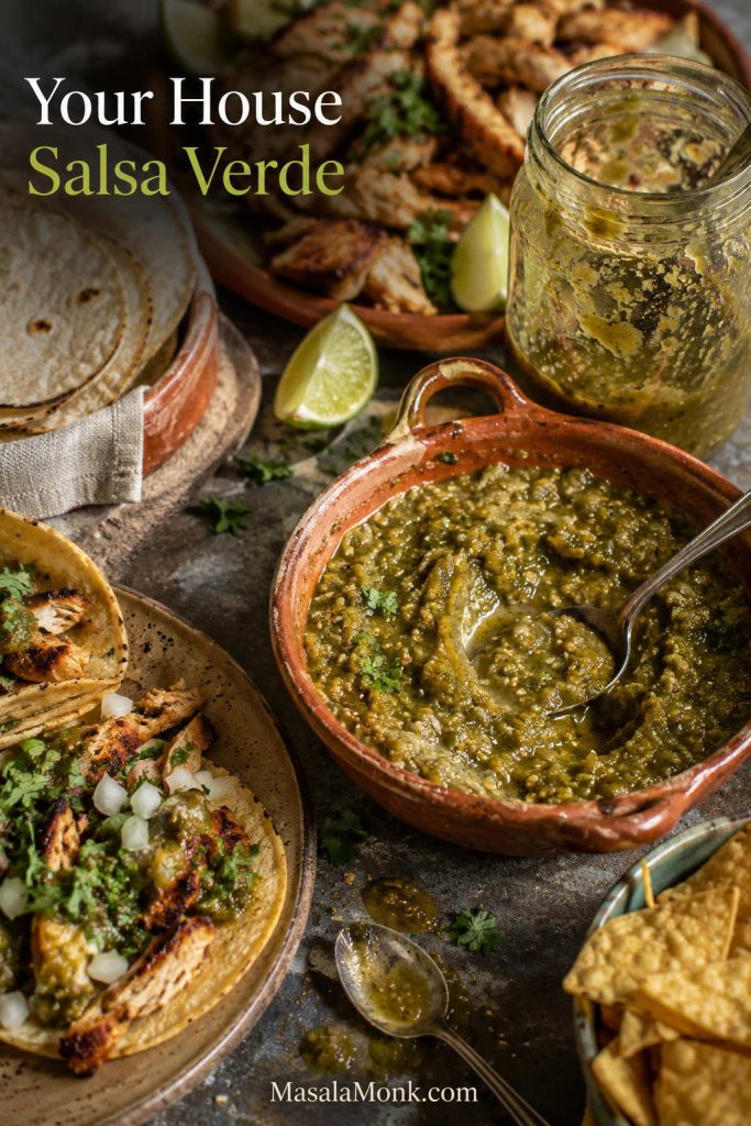 Used table scene with a bowl and jar of salsa verde, tacos, tortilla chips, lime wedges, tortillas, and grilled chicken