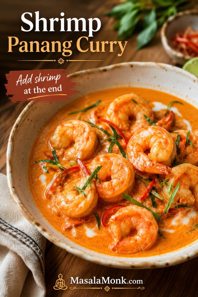 Shrimp Panang curry with curled shrimp in creamy orange-red coconut curry sauce, Thai basil, red chile, and lime leaf garnish.