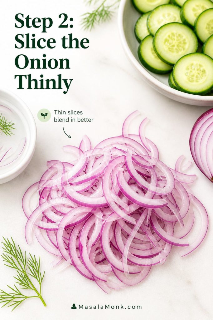 Thinly sliced red onion for cucumber salad, with cucumber and dill nearby.