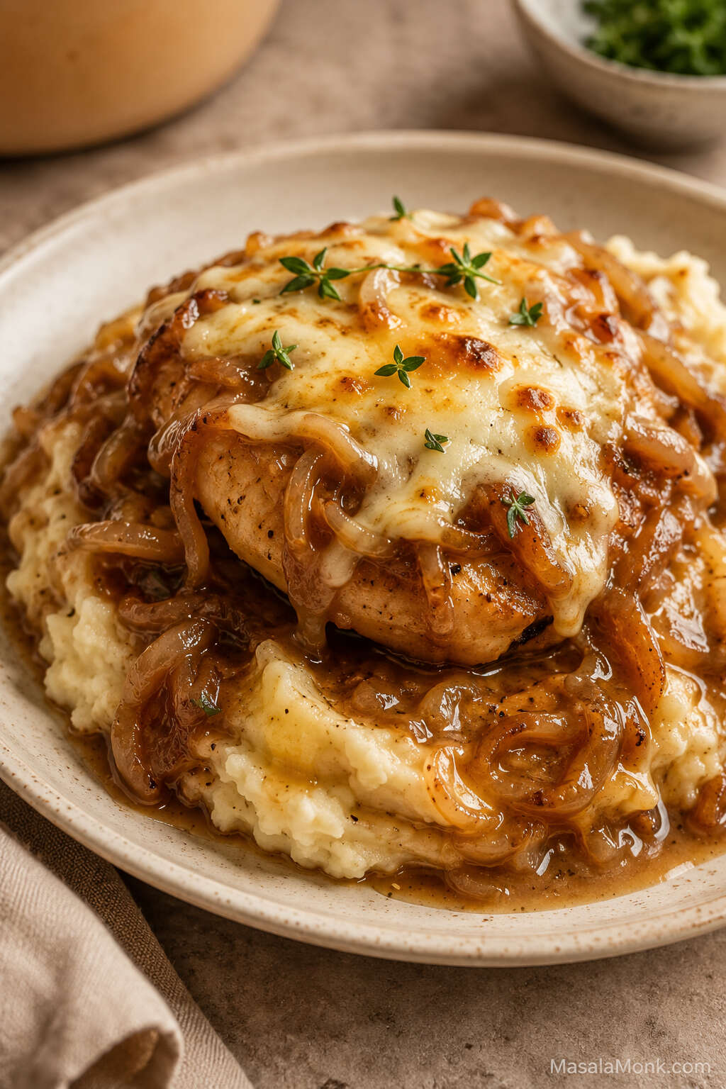 Slow cooker French onion chicken with melted cheese, soft onions, and onion gravy served over creamy mashed potatoes.