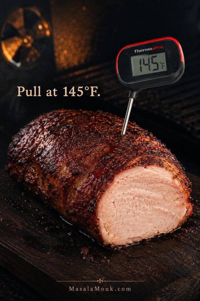 Smoked pork loin reaching 145°F internal temperature with a thermometer in the roast