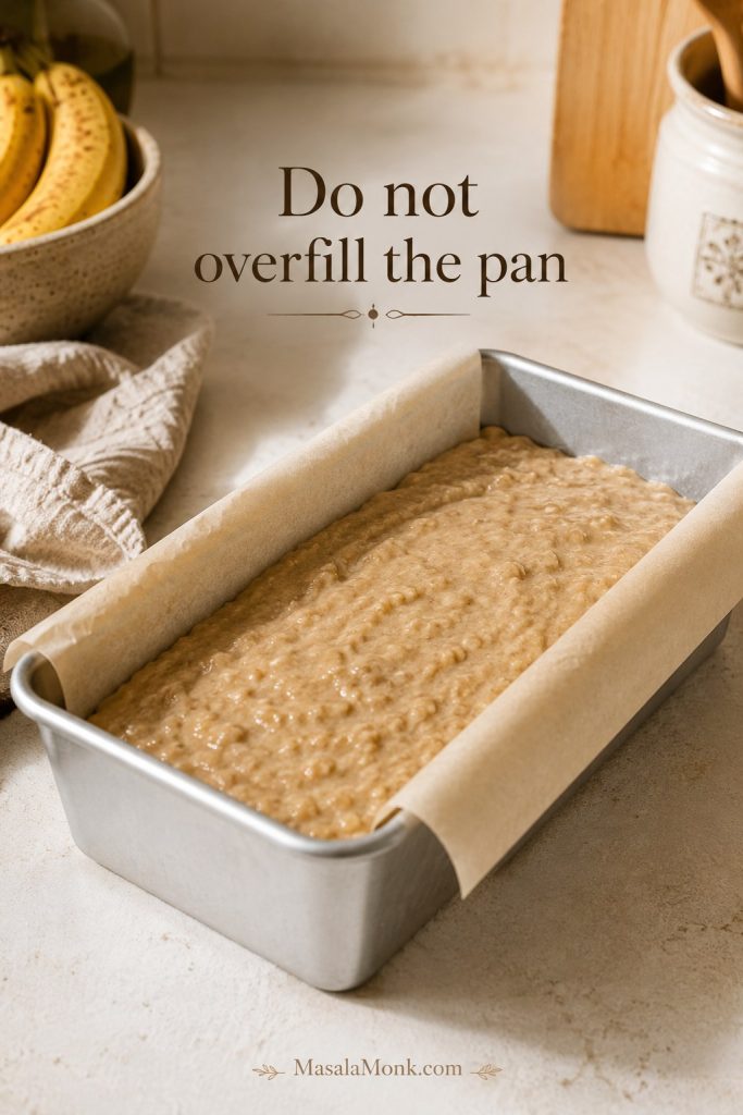 Sourdough banana bread batter spread in a parchment-lined light metal loaf pan with the text “Do not overfill the pan.”