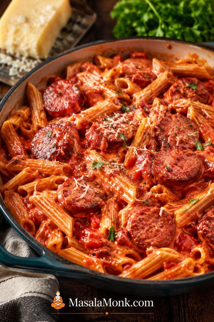 Tomato-cream kielbasa pasta with browned sausage slices, short pasta, red creamy sauce, herbs, and grated cheese.
