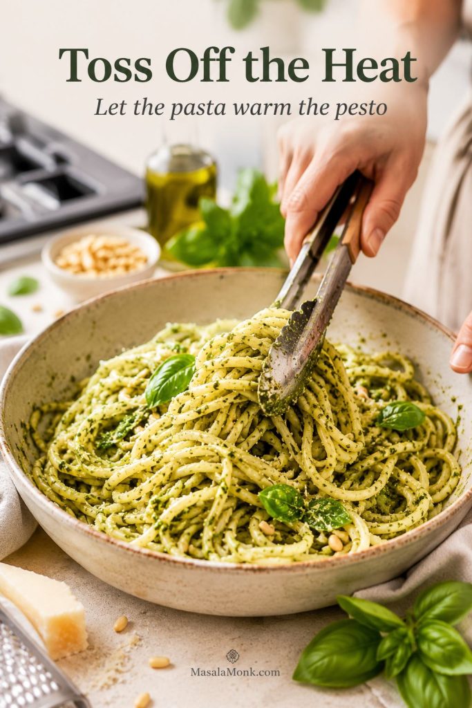 Pesto pasta being tossed in a bowl away from the stove so the sauce warms gently