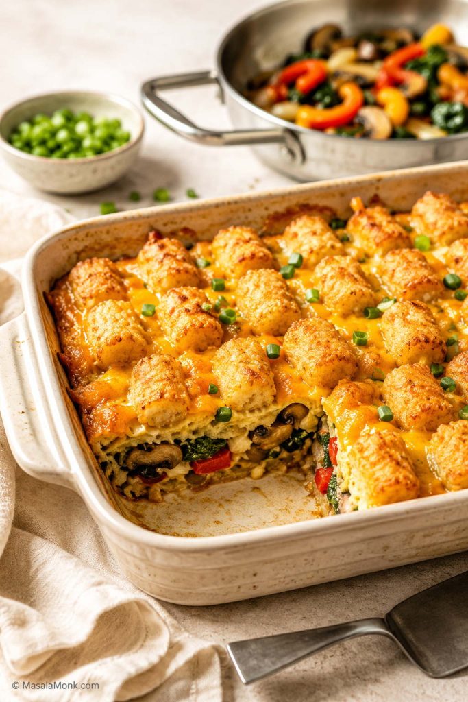 Vegetarian tater tot breakfast casserole with mushrooms, peppers, spinach, onions, eggs, cheese, and browned tater tots.
