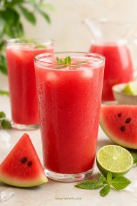Cold watermelon juice served in clear glasses with ice, watermelon wedges, lime, and mint on a bright summer surface.