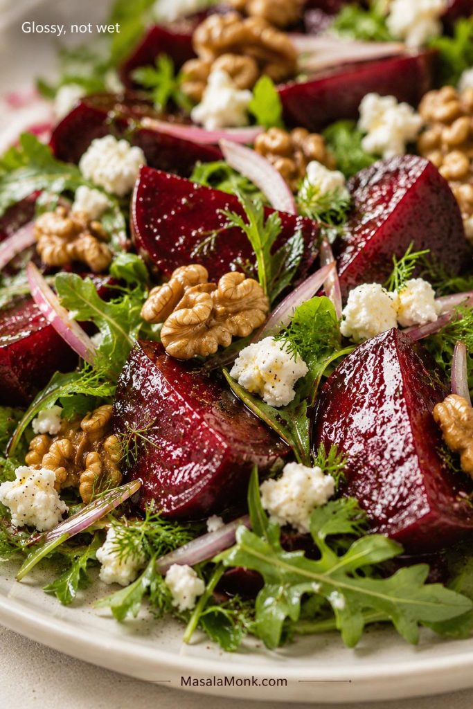 Close-up of roasted beet salad with glossy beets, greens, feta, walnuts, herbs, and the words “Glossy, not wet.”