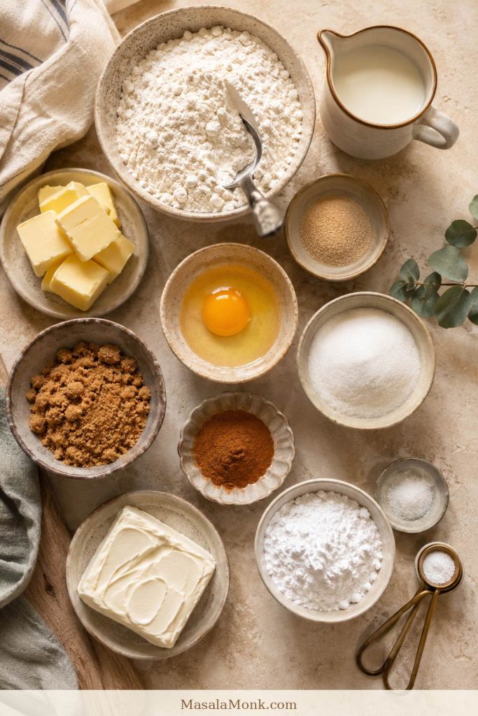Ingredients for homemade cinnamon rolls including flour, milk, butter, eggs, yeast, sugar, and cinnamon