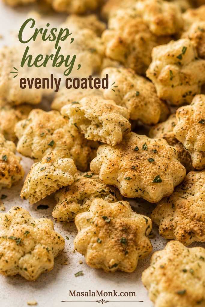 Close-up of crisp ranch oyster crackers with toasted edges, broken pieces, and green herb flecks.