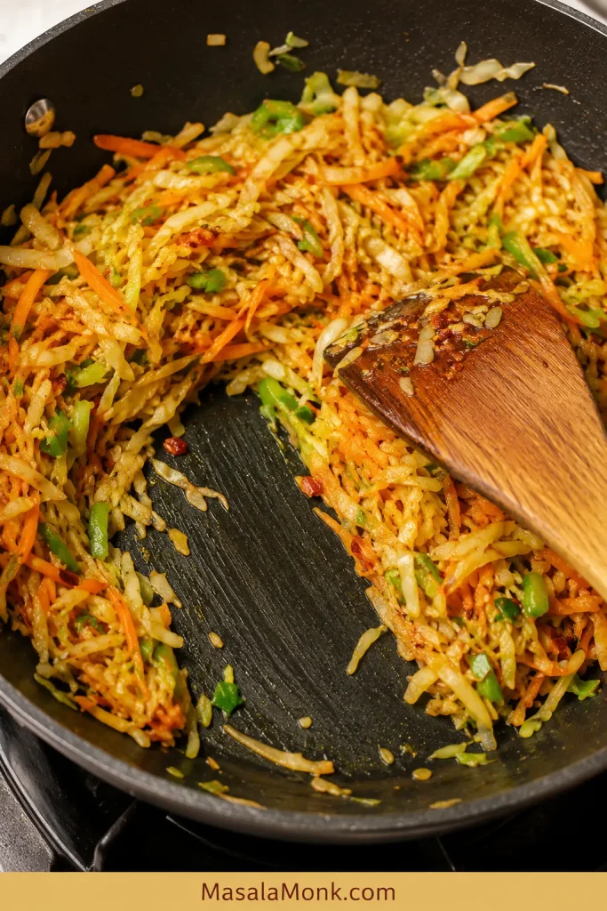 Cooked vegetable spring roll filling pushed aside in a pan with no loose liquid visible.